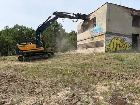 Demolácia budovy pásovým rýpadlom